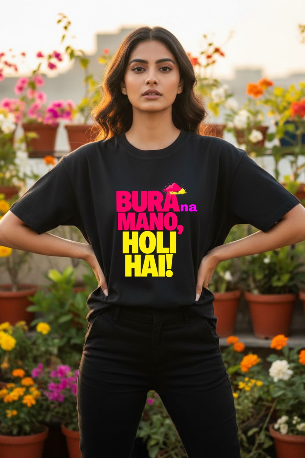 Woman wearing a black oversized t-shirt with colorful text " bura na mano holi hai" in a garden setting