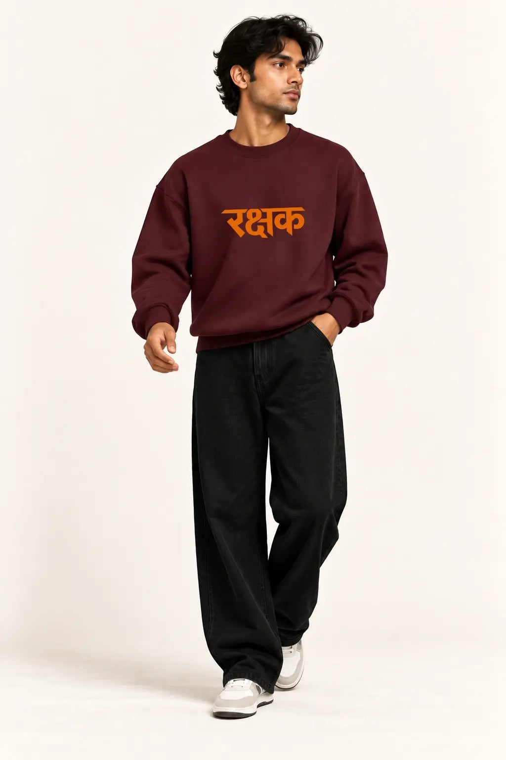 Rakshak Lord Hanuman oversized sweatshirt in maroon with orange Devanagari Rakshak print on the front, styled with black baggy jeans and white sneakers | JUNOSHI