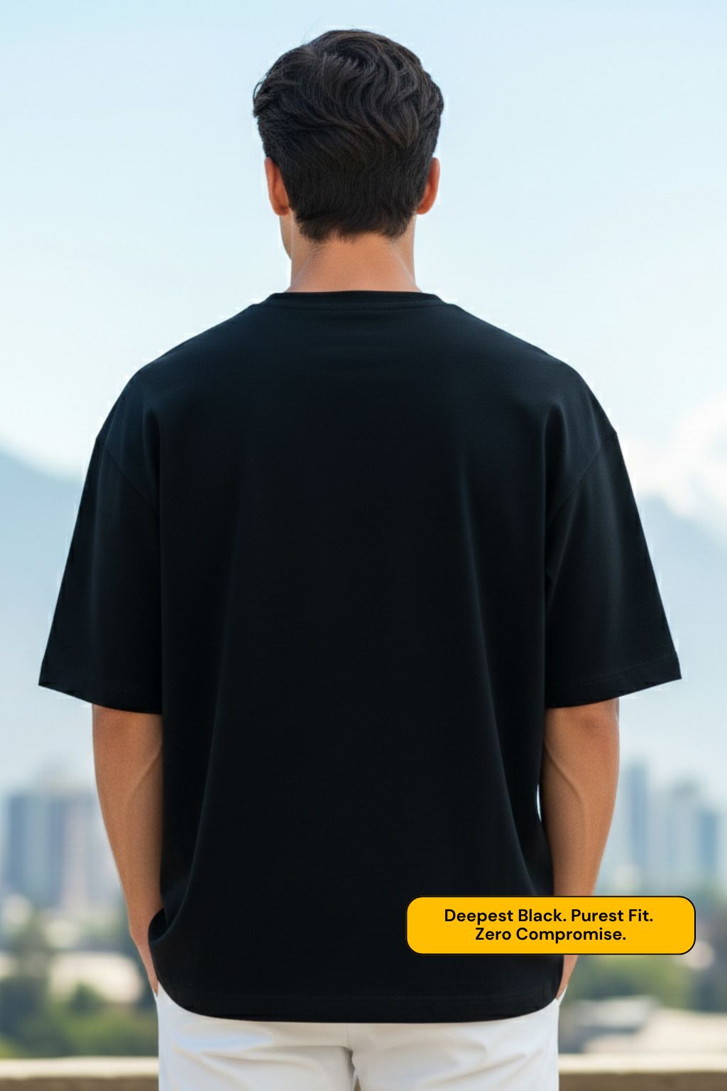 back view of a man wearing a black oversized t-shirt with a scenic background