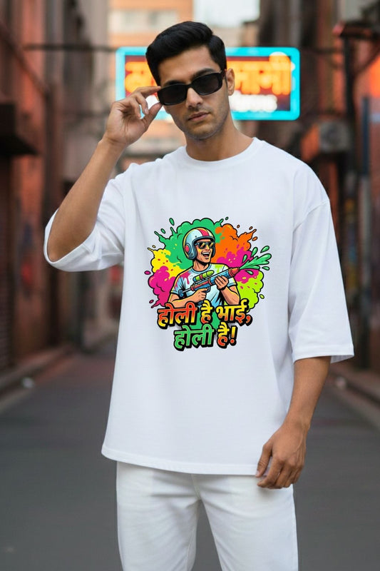 Man wearing a white oversized t-shirt with colorful graphic design and text " Holi hai bhai, holi hai" , standing in an urban setting.