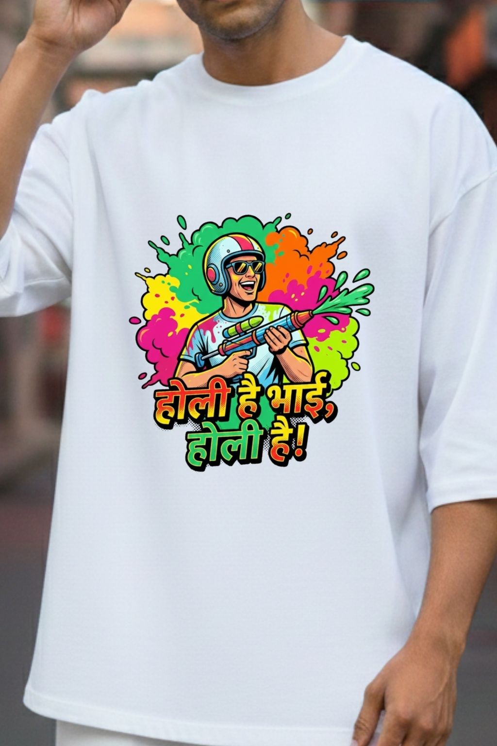 close up view of a white oversized t-shirt with colorful graphic and text " Holi hai bhai, holi hai" , worn by a man.