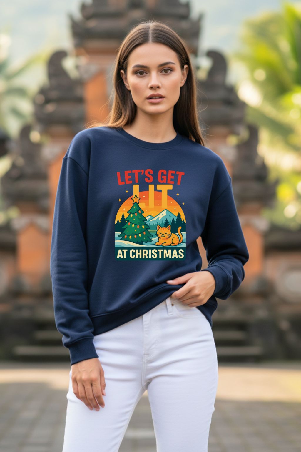 Woman wearing a navy blue oversized sweatshirt with a Christmas design in front of a blurred background
