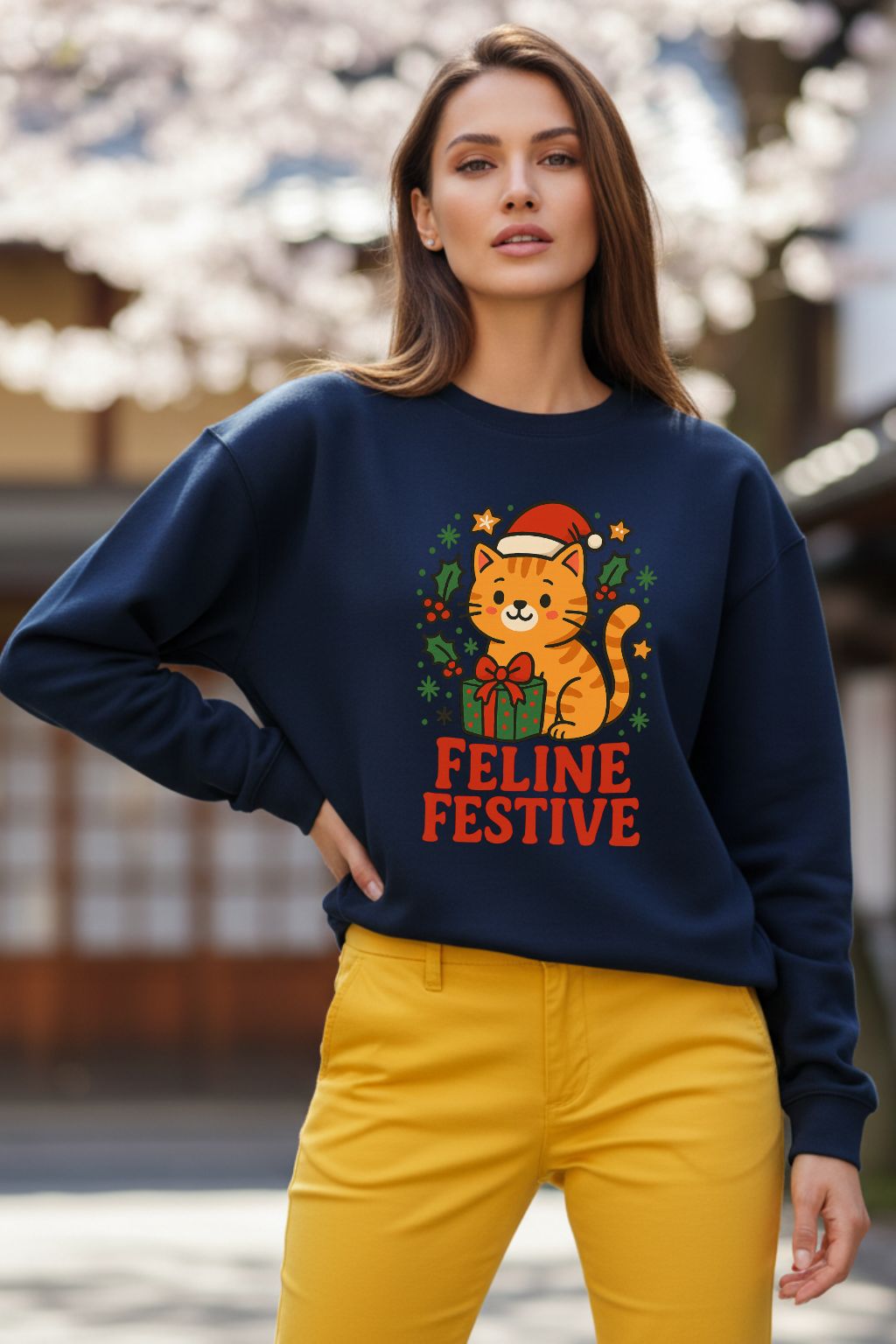 Woman wearing a navy blue oversized sweatshirt with a feline graphic and 'Feline Festive' text, standing outdoors.