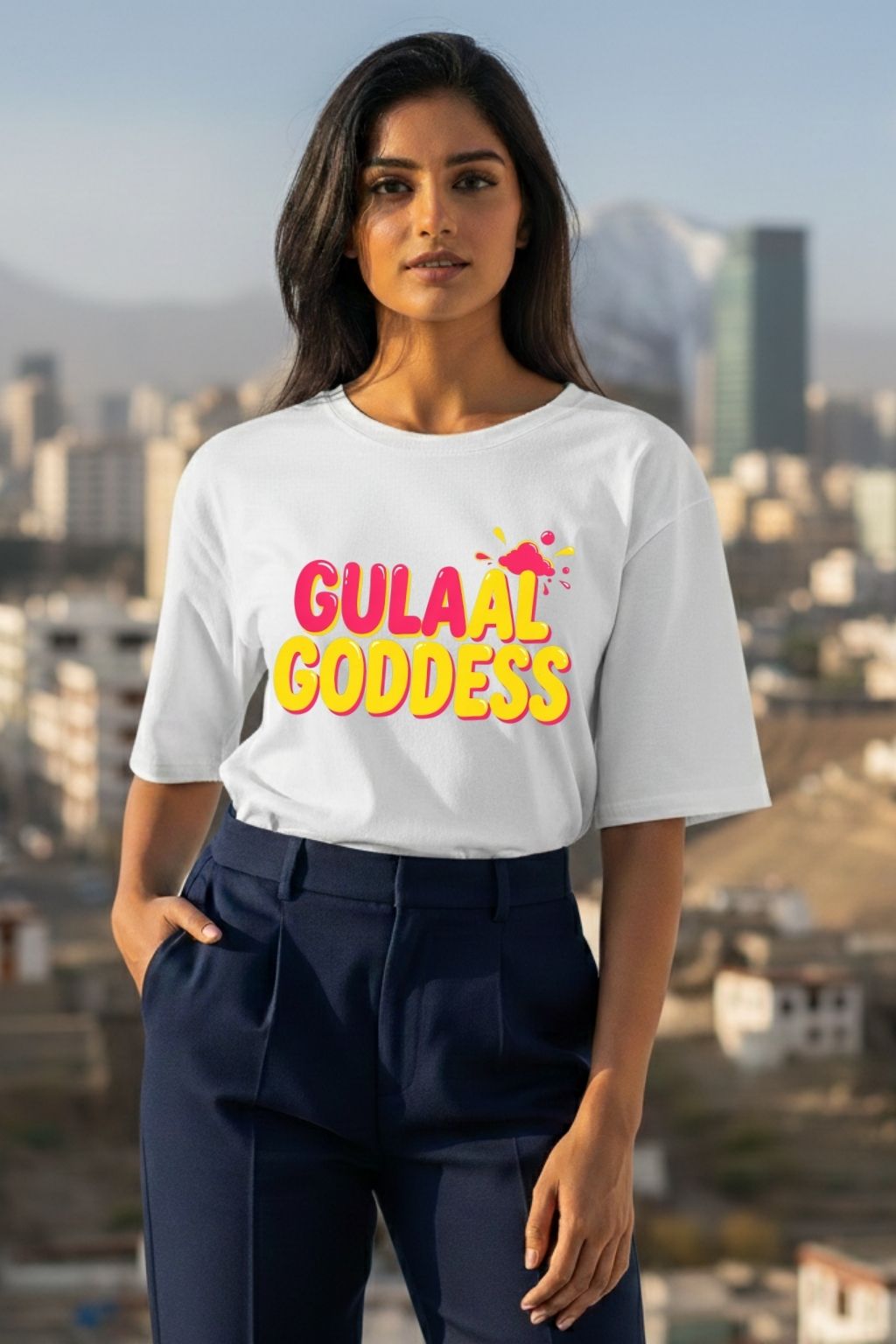 Woman wearing a white oversized t-shirt with 'Gulaal Goddess' text, standing in front of a cityscape.