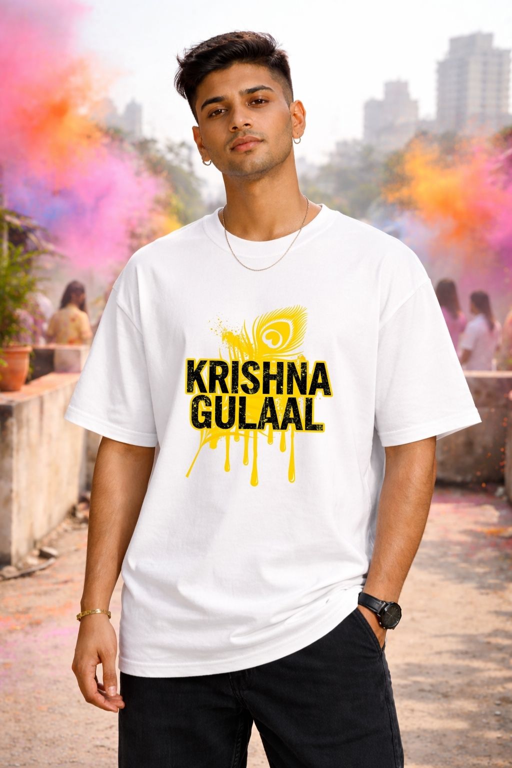 Man wearing a white oversized t-shirt with 'Krishna Gulaal' print in a colorful outdoor setting