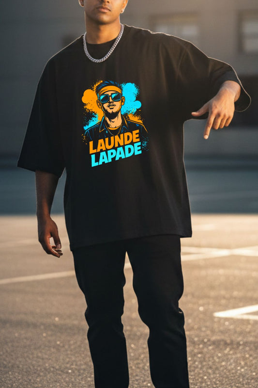 close up view of a man wearing a black oversized t-shirt with a colorful graphic and text "Launde Lapade", standing outdoors.