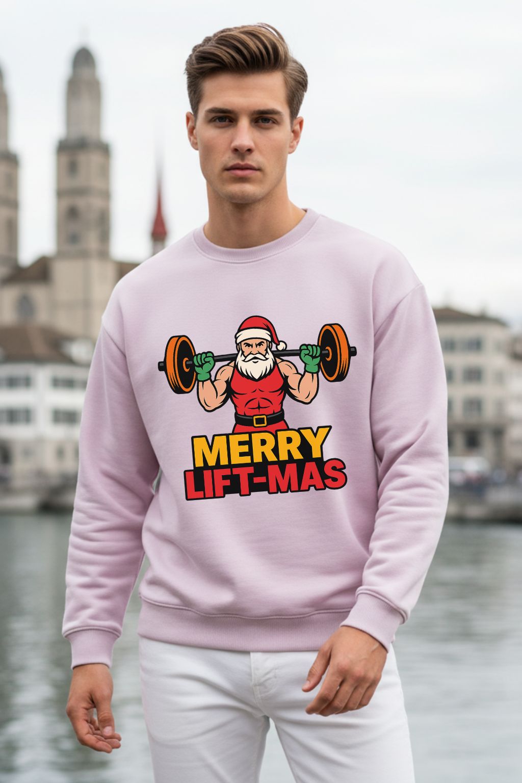 Man wearing a light baby pink oversized sweatshirt with a Christmas-themed graphic and text, standing in front of a cityscape.