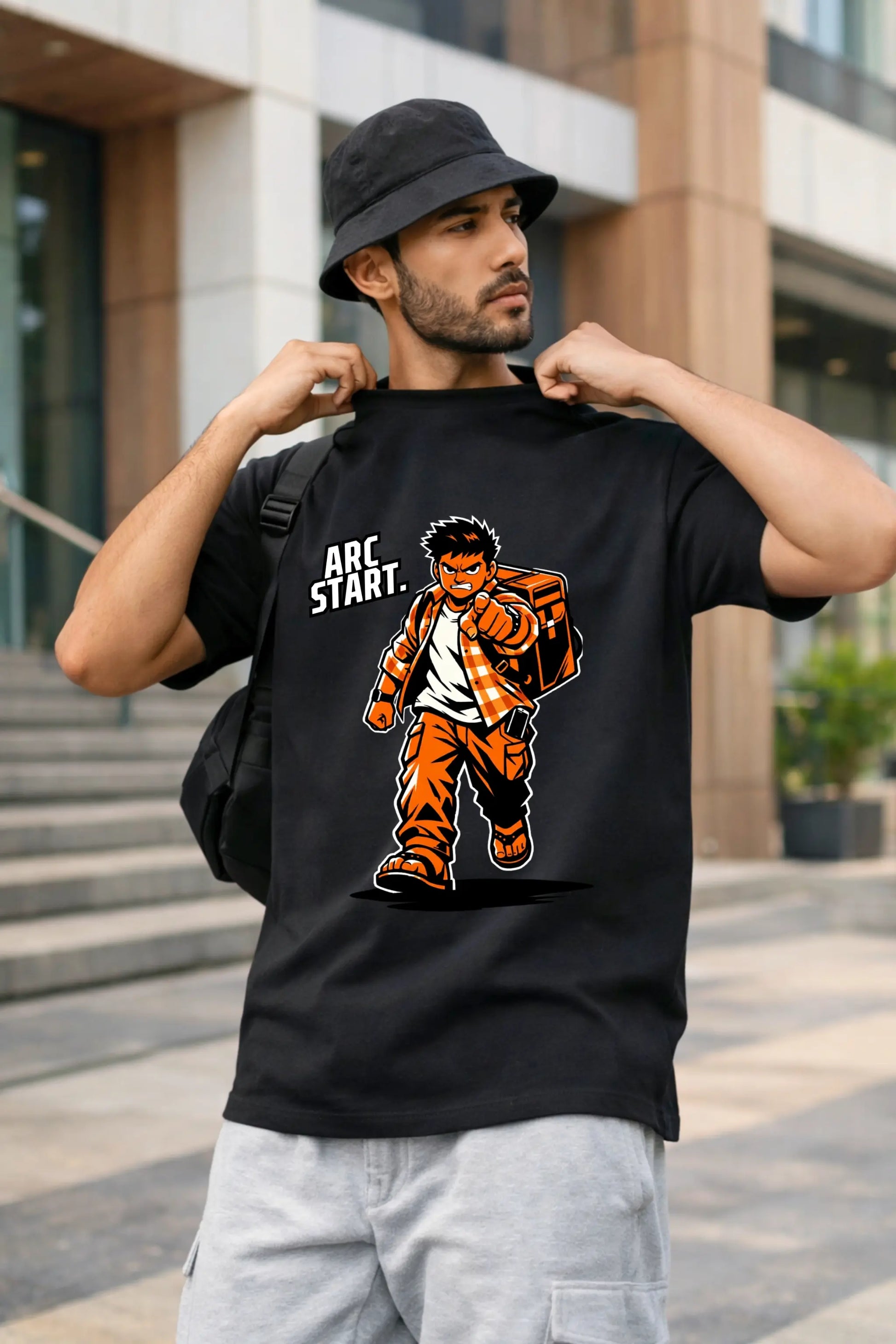 Arc Start anime oversized T-shirt in black — desi guy in bucket hat and backpack wearing bold shonen graphic tee by JUNOSHI
