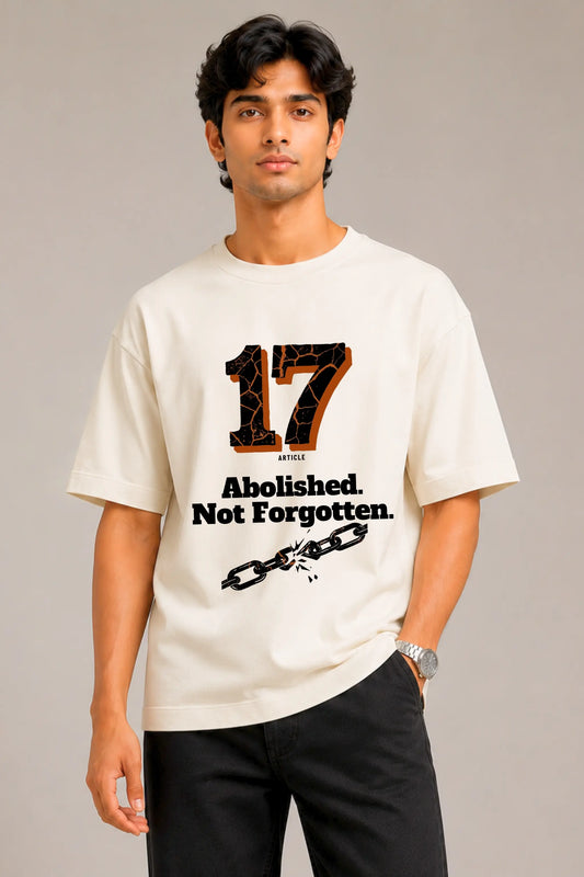 Man wearing oversized cream Article 17 t-shirt with Abolished Not Forgotten print — Written in Stone collection by JUNOSHI