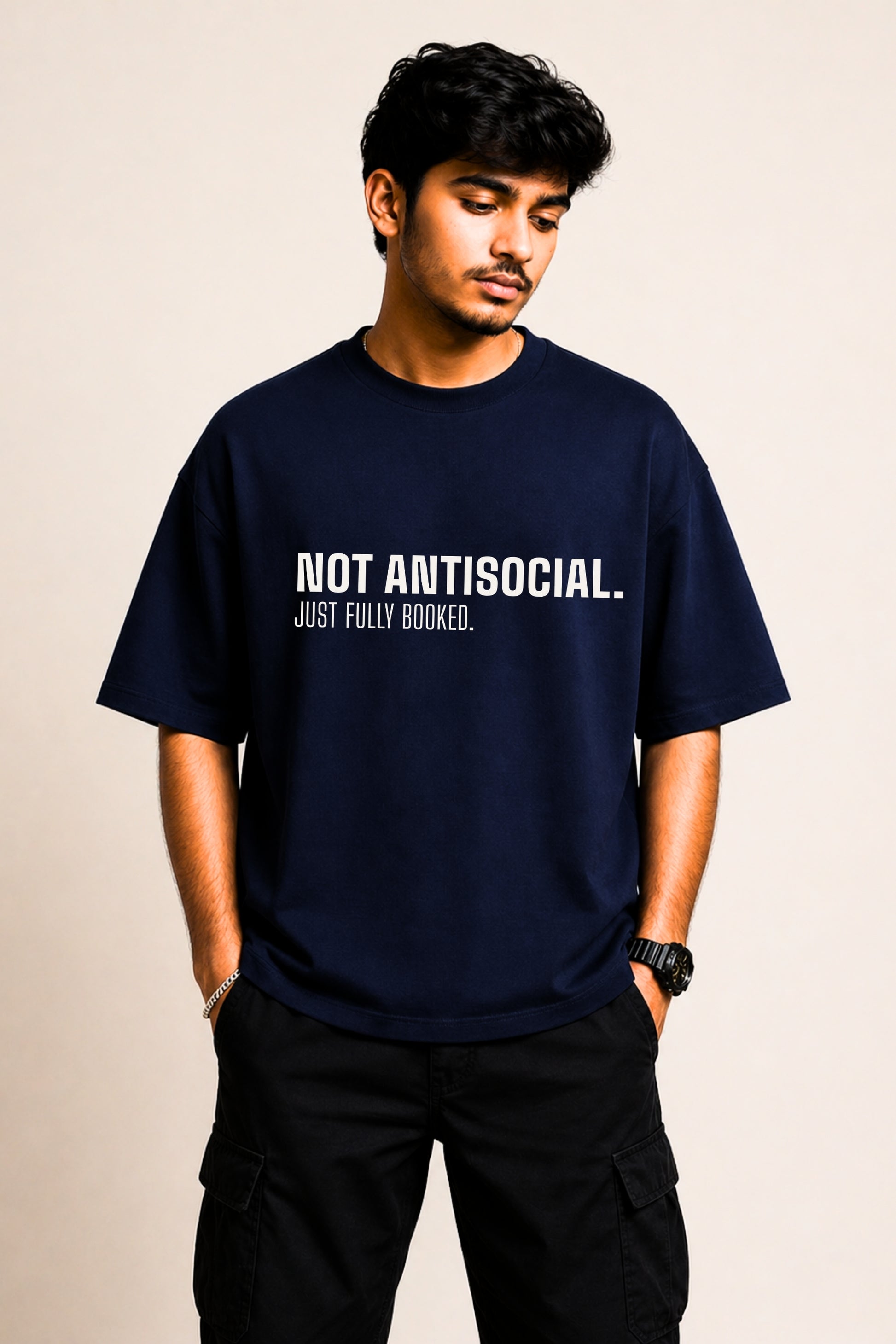 Navy oversized graphic tee with bold text "Not Antisocial. Just Fully Booked." worn by a man — JUNOSHI Unfiltered Collection
