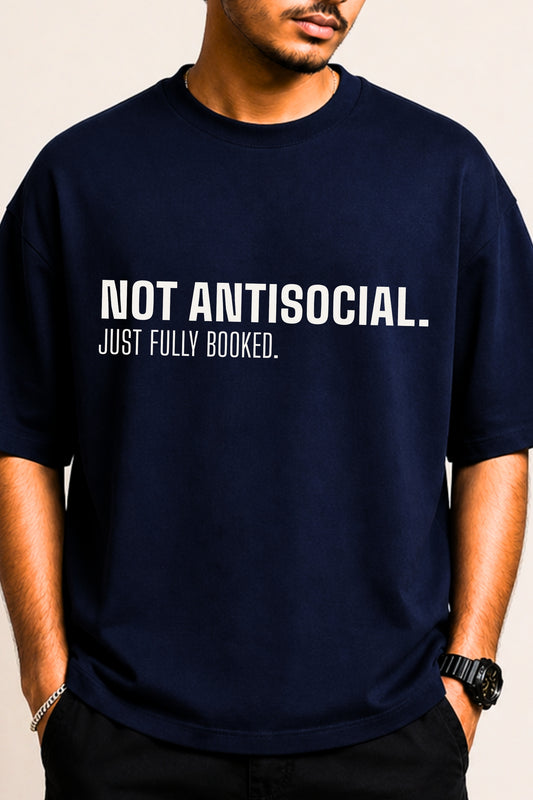 Close-up of bold white typography print "Not Antisocial. Just Fully Booked." on navy oversized tee — JUNOSHI