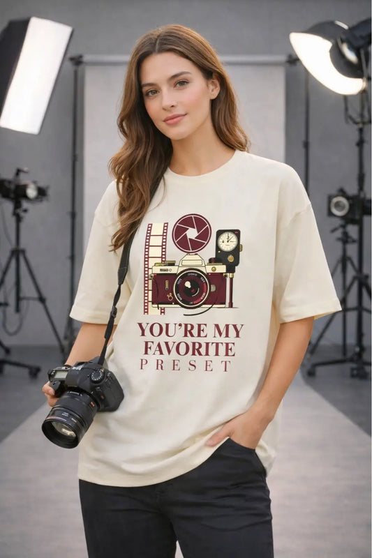 Female photographer holding DSLR camera wearing JUNOSHI You're My Favorite Preset oversized cream tee in photography studio — Valentine's Day gift for photographers