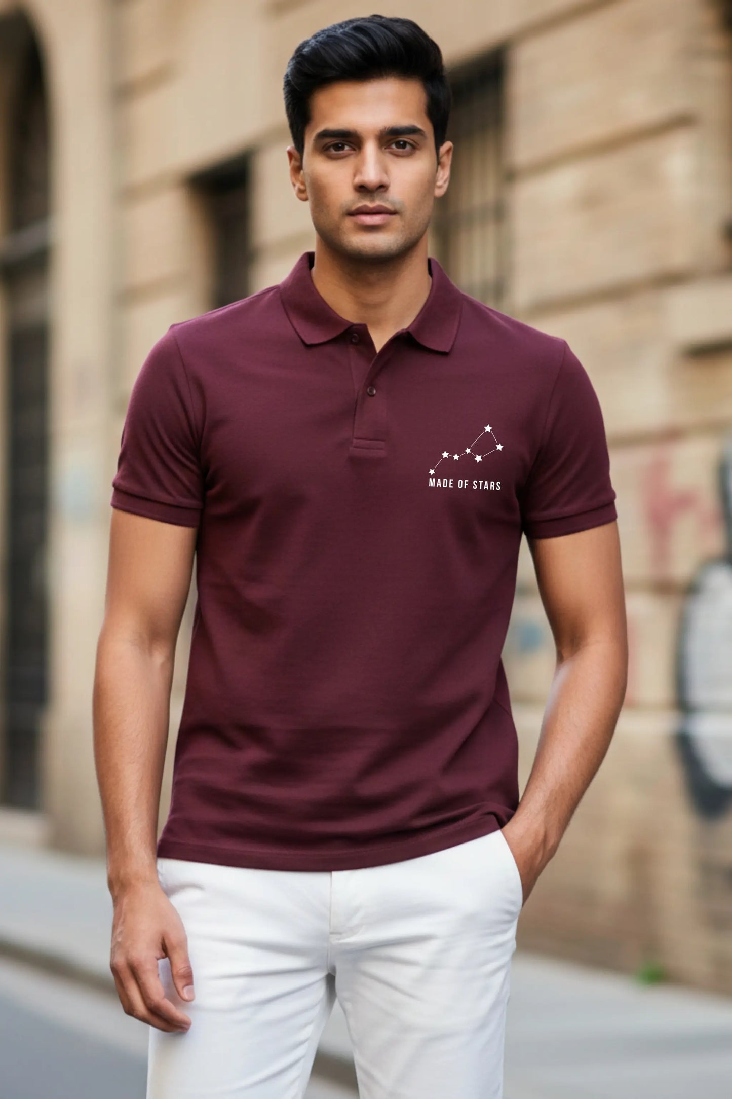 JUNOSHI Made of Stars maroon polo — Indian man wearing constellation graphic polo with white chinos, street style shot against urban building backdrop