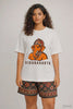 Woman wearing the Vighnaharta Ganesha Oversized T-Shirt by JUNOSHI — bold orange Ganesha graphic with 'Vighnaharta' text on white unisex tee, part of the Divine Street collection