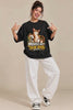 Woman in black Moved In Took Over Indie Cat oversized terry t-shirt and white wide-leg pants winks, points at the cat print and strikes a playful pose | JUNOSHI