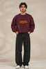 Video of a model in a maroon Rakshak Lord Hanuman oversized sweatshirt with orange Devanagari lettering on the front, then turning to show the Lord Hanuman gada illustration on the back, styled with black baggy jeans | JUNOSHI