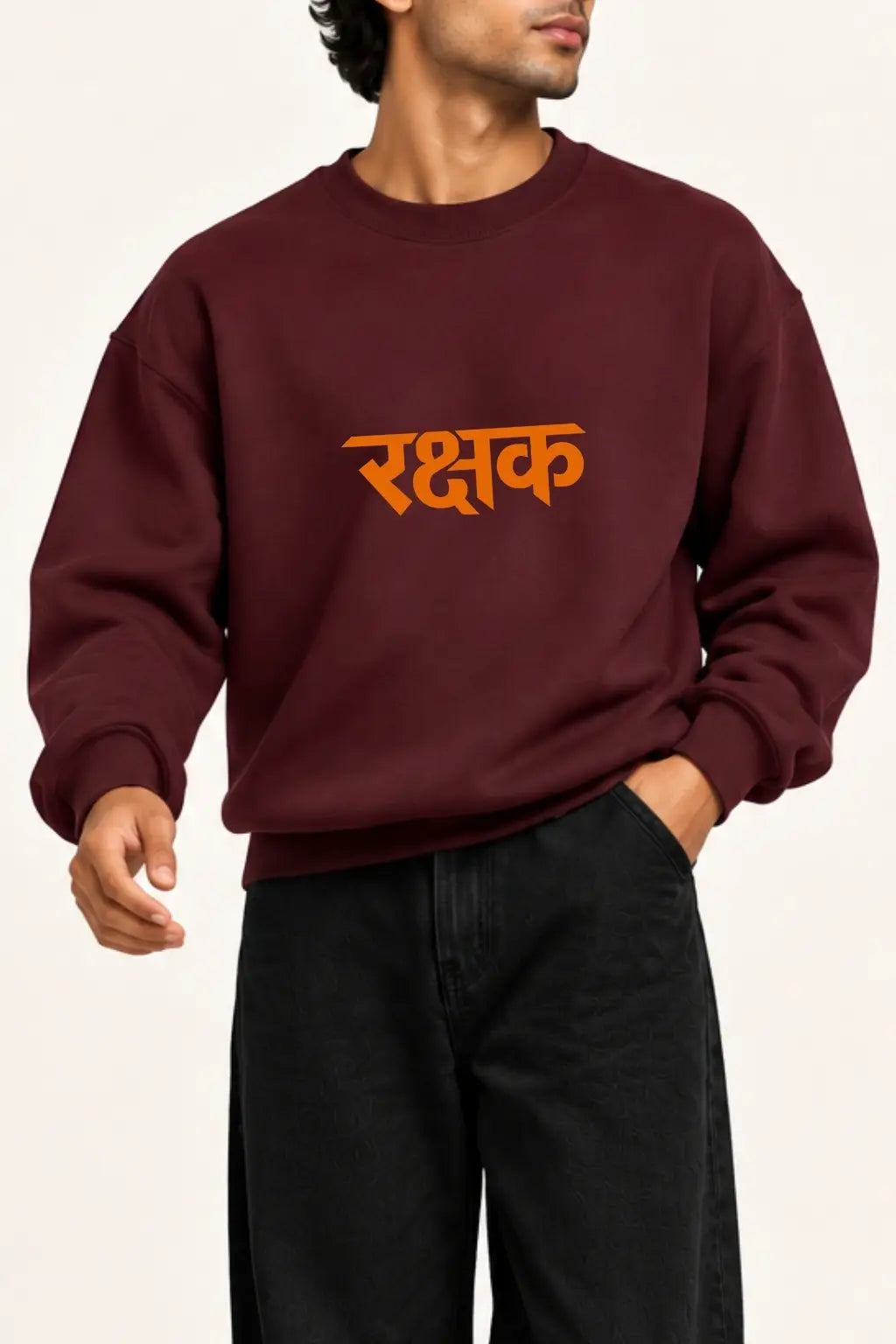 Close-up of the orange Rakshak Devanagari lettering on a maroon unisex oversized sweatshirt, front chest print | JUNOSHI