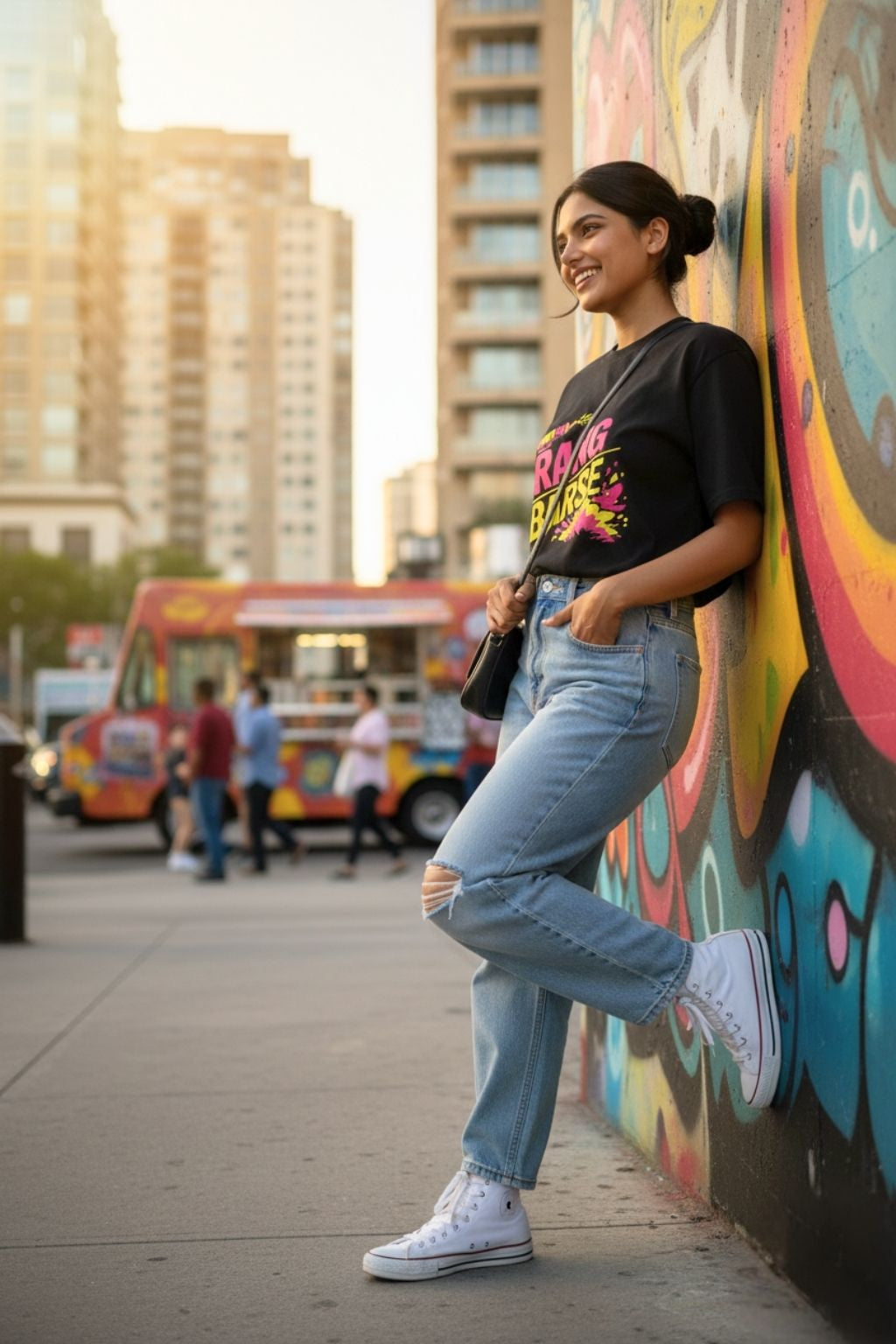 Woman in street style wearing Rang Barse black oversized Holi t-shirt against colourful urban mural — JUNOSHI